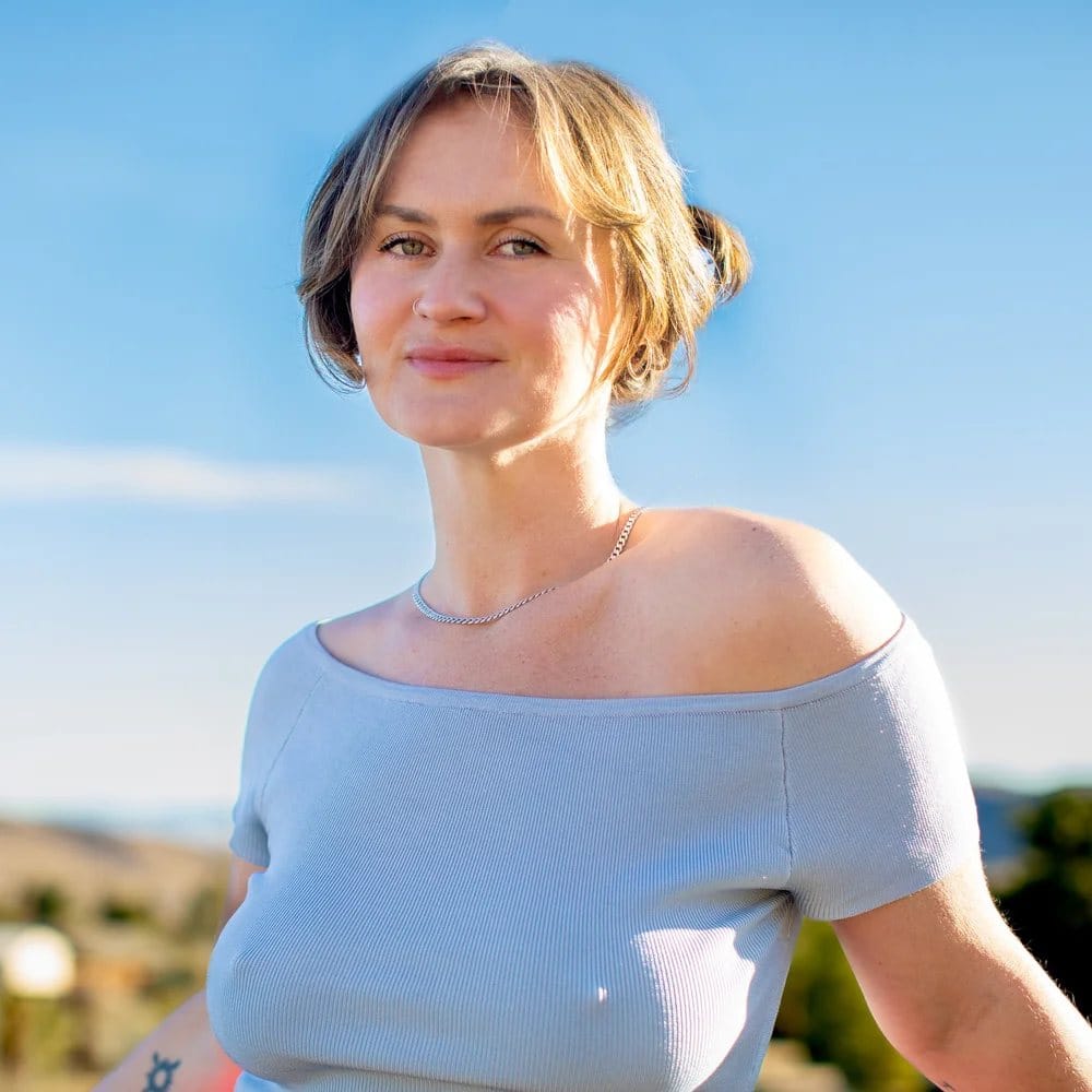 A woman standing in open air, sunlit against the sky
